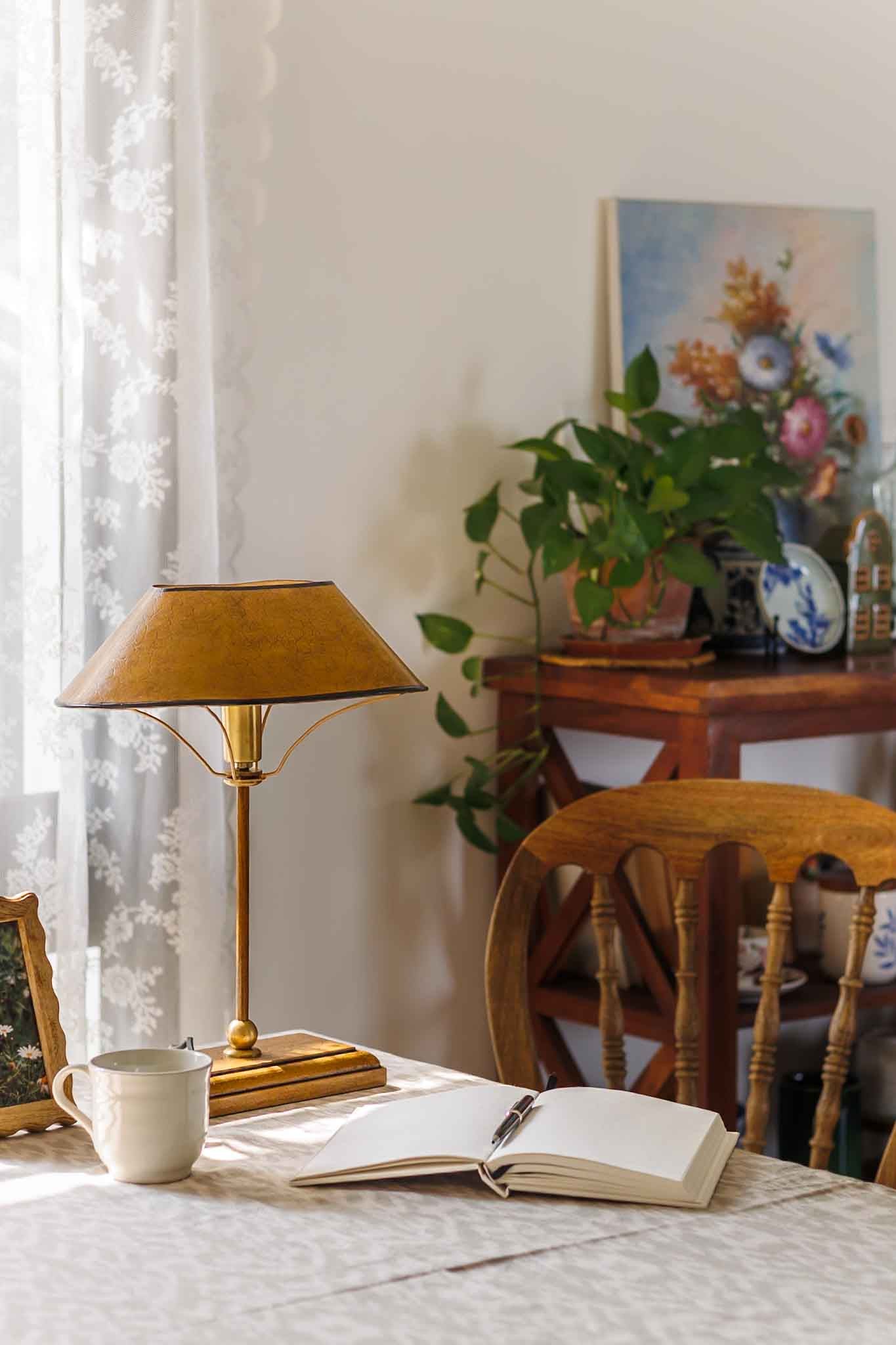 Home office setup with a lamp, open book, and cup on a desk.