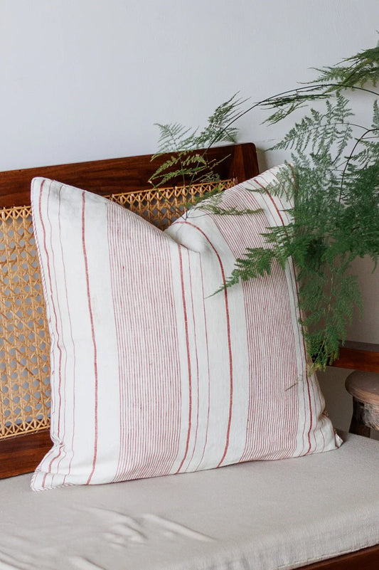 Striped pillow on a wicker bench with greenery