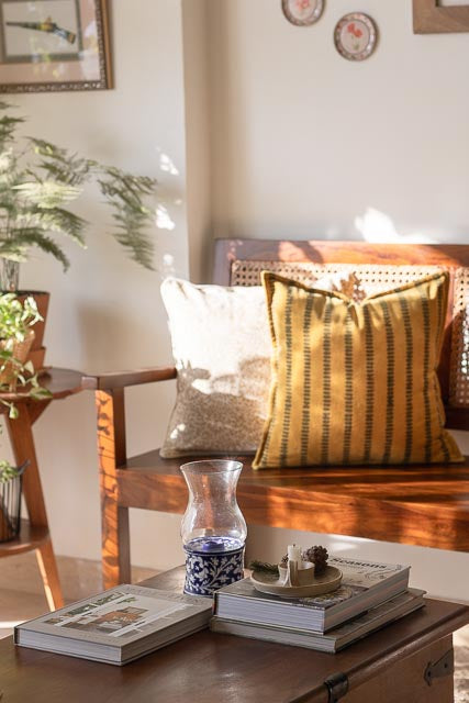 Cozy living room with a wooden bench, decorative pillows, and a vase.