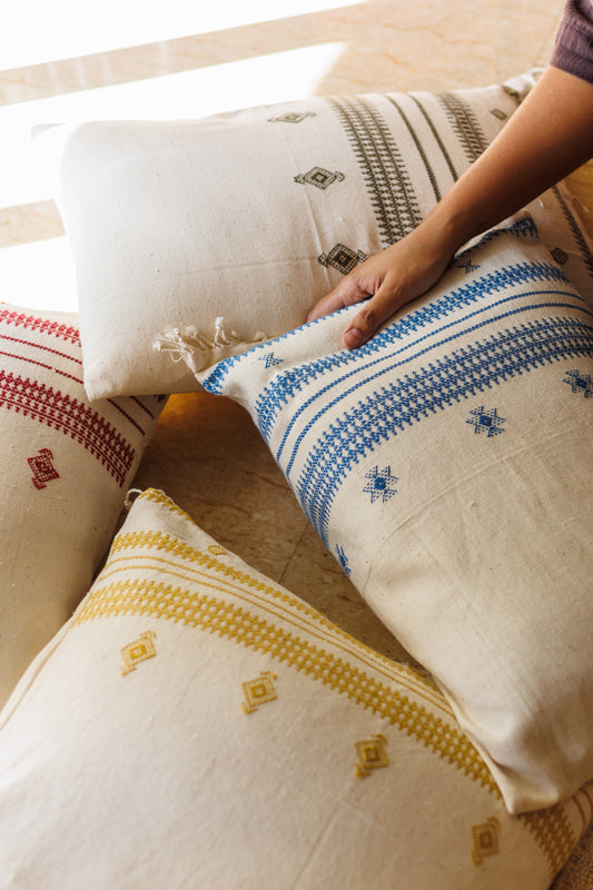 Colourful Bhujodi Hand woven organic cotton cushion stack with a hand on them