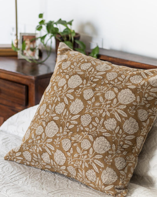 Mustard floral Block Print cushion on a bed with a plant in background
