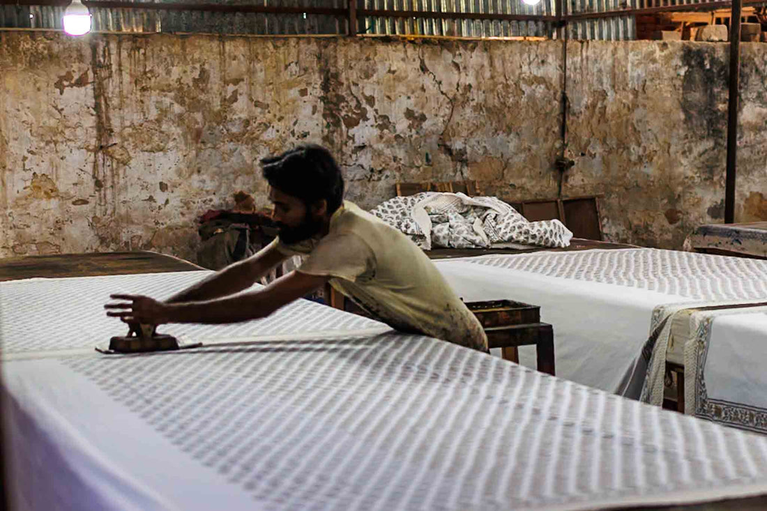 An artisan block printing on fabric inside a workshop in jaipur