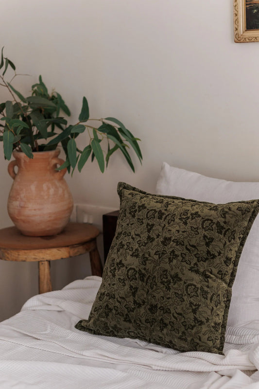 Forest Green Velvet Cushion Cover on a Bed with a Terracotta Vase and leaves inside it