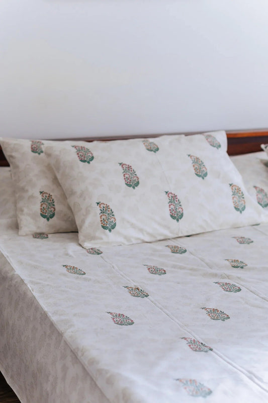 Block Print Boota bed sheet with two pillows on a wooden bed