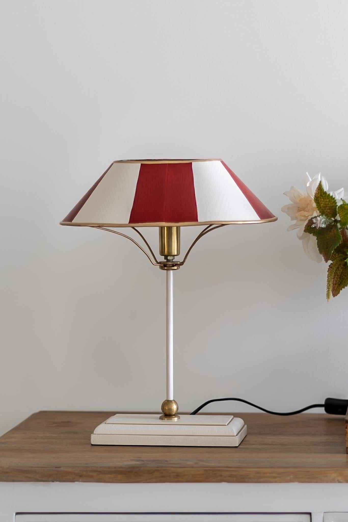 Table lamp with a red and white striped shade on a wooden surface.