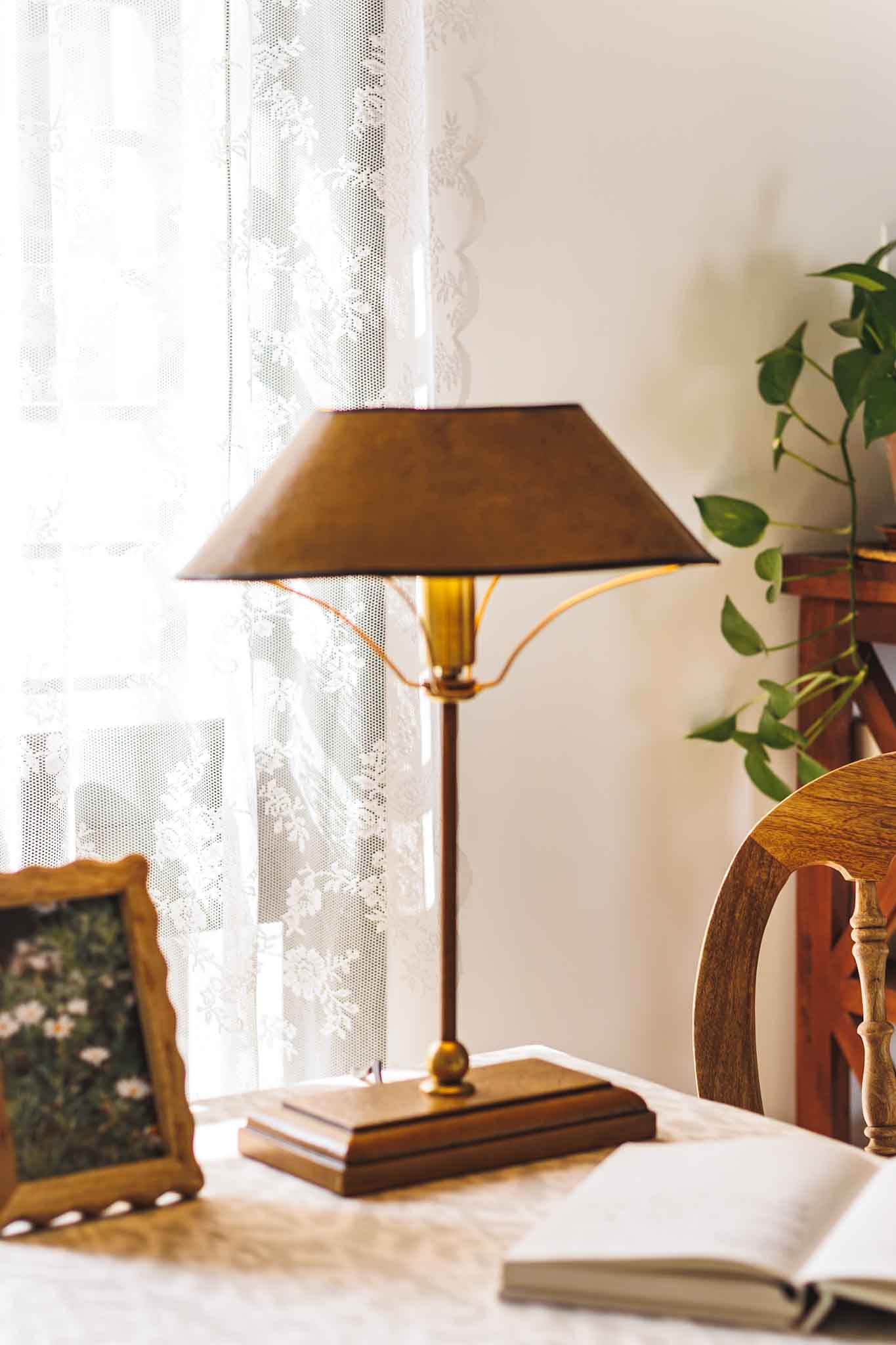 Vintage-style lamp on a table with a window and plant in the background