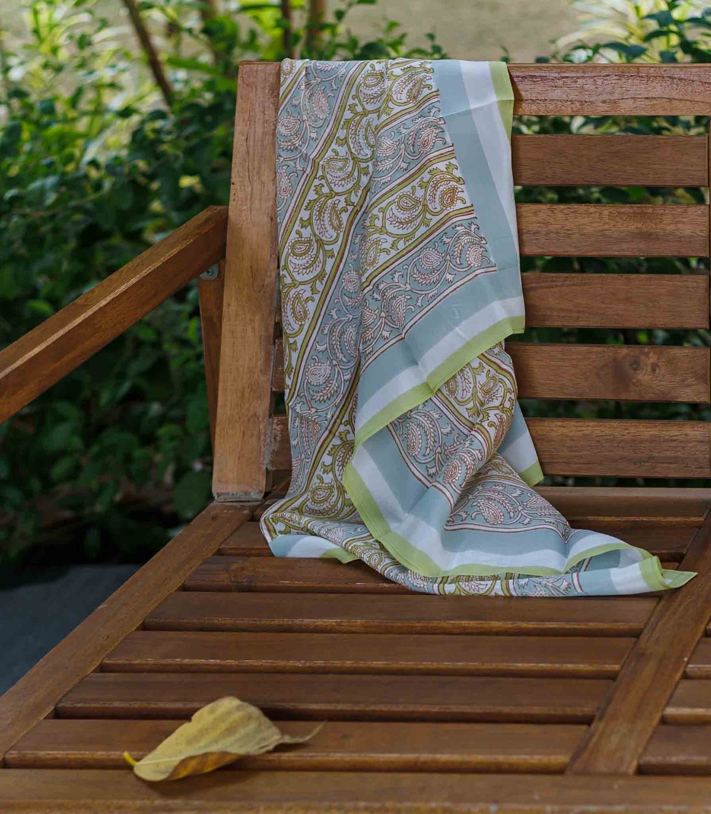 Block Print Patterned silk scarf draped over a wooden chair with a garden background