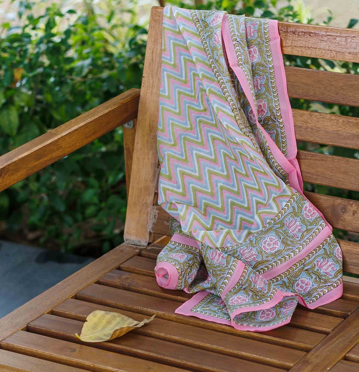 Block Print Patterned silk scarf draped over a wooden chair with a garden background