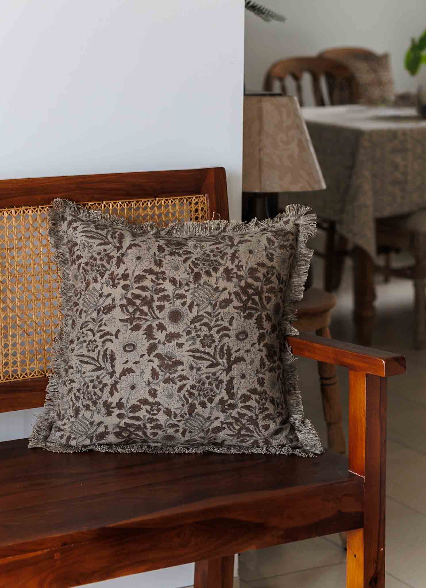 Decorative pillow with floral pattern on a wooden bench in a room setting.