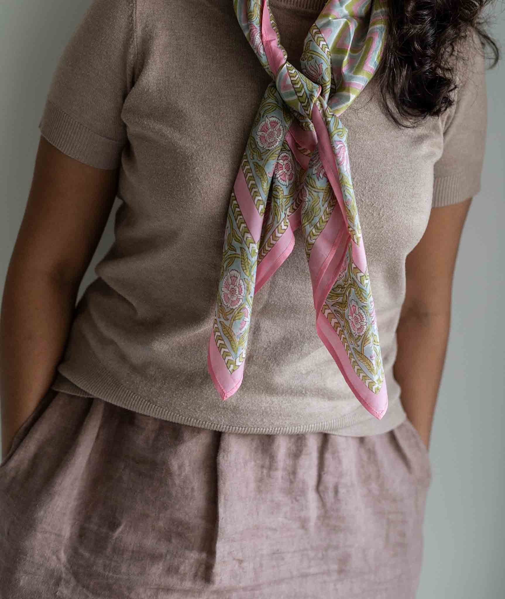 Person wearing a patterned pink scarf with a neutral background