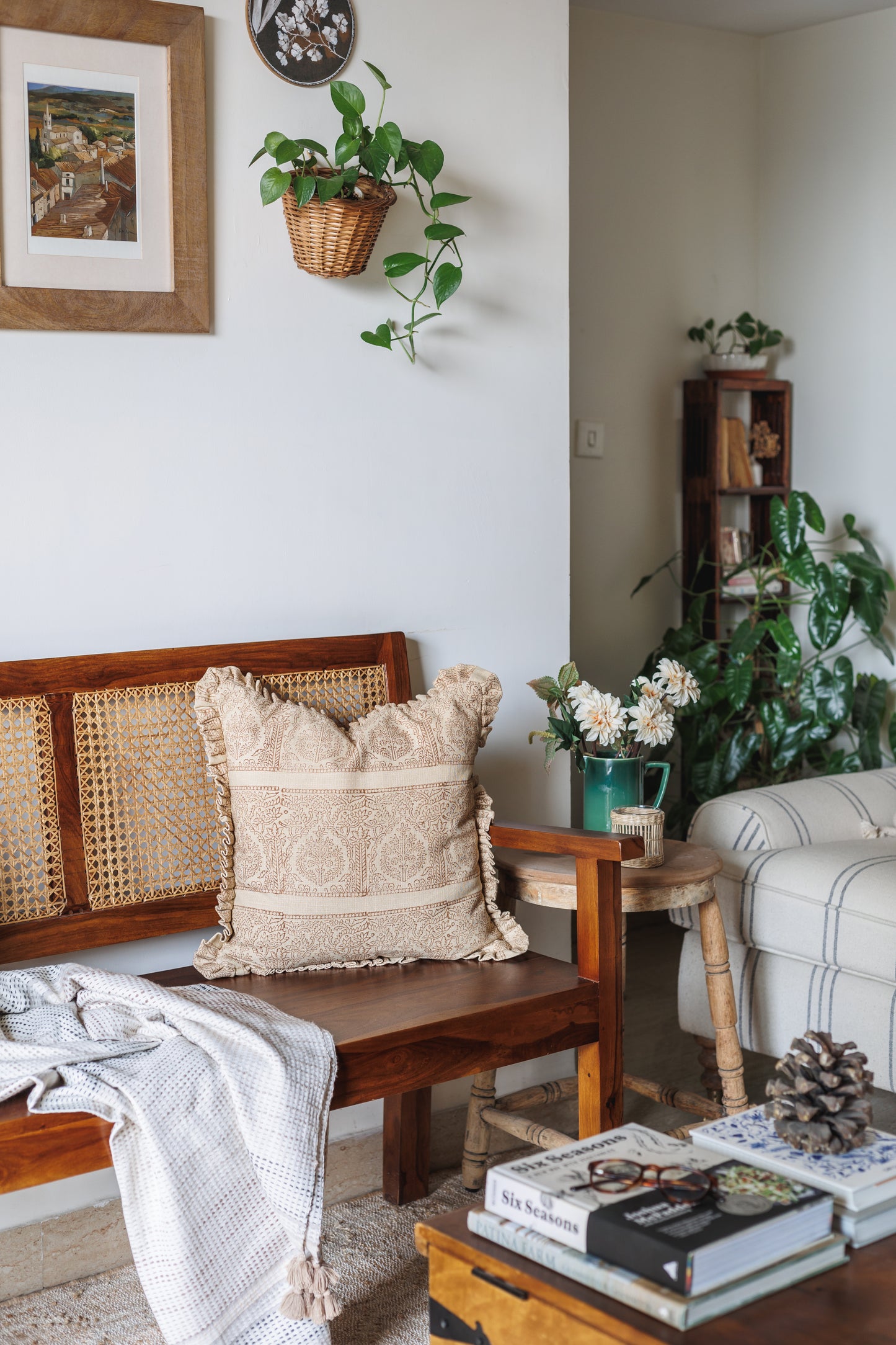 Cozy living room with wooden bench, block print cushion, and books on a coffee table.