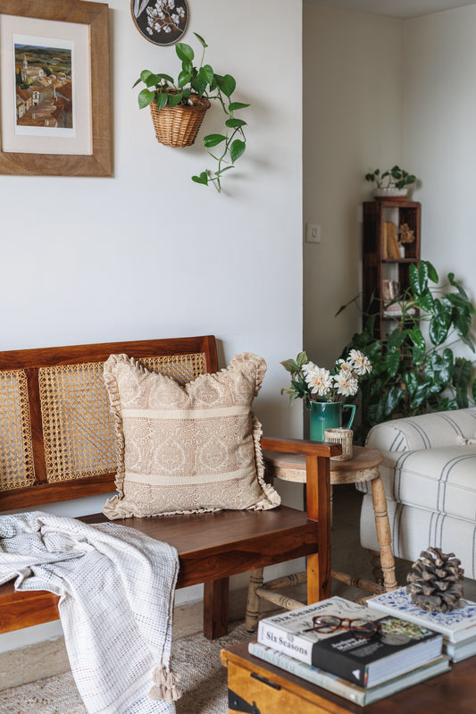 Cozy living room with wooden bench, block print cushion, and books on a coffee table.
