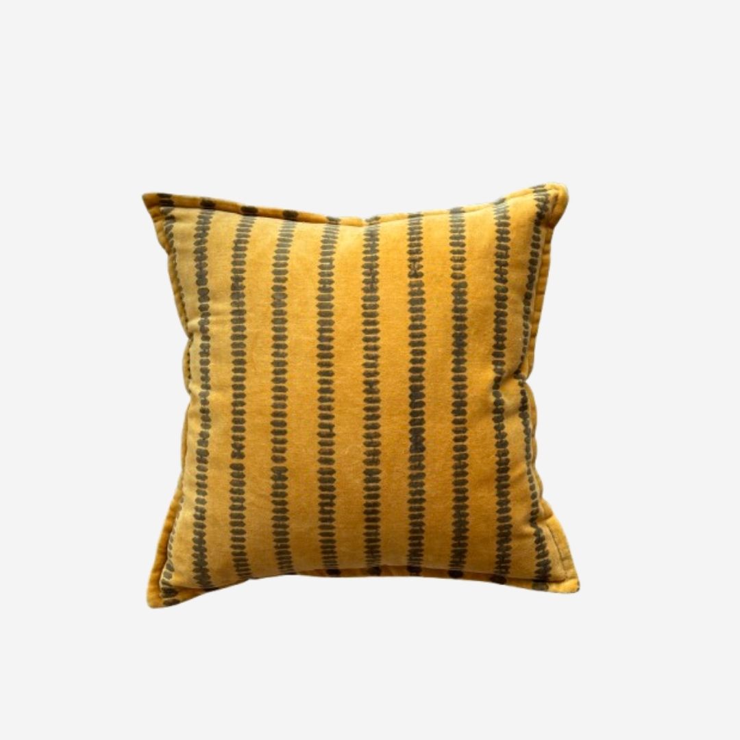 A square throw pillow in mustard yellow velvet with vertical black dotted stripes, shown against a plain light gray background.