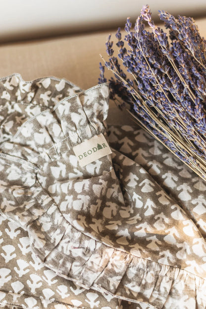 Floral-patterned fabric with a brand label next to dried lavender on a wooden surface.