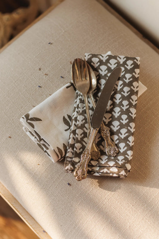 Silver spoon and knife on a patterned napkin with a rustic background