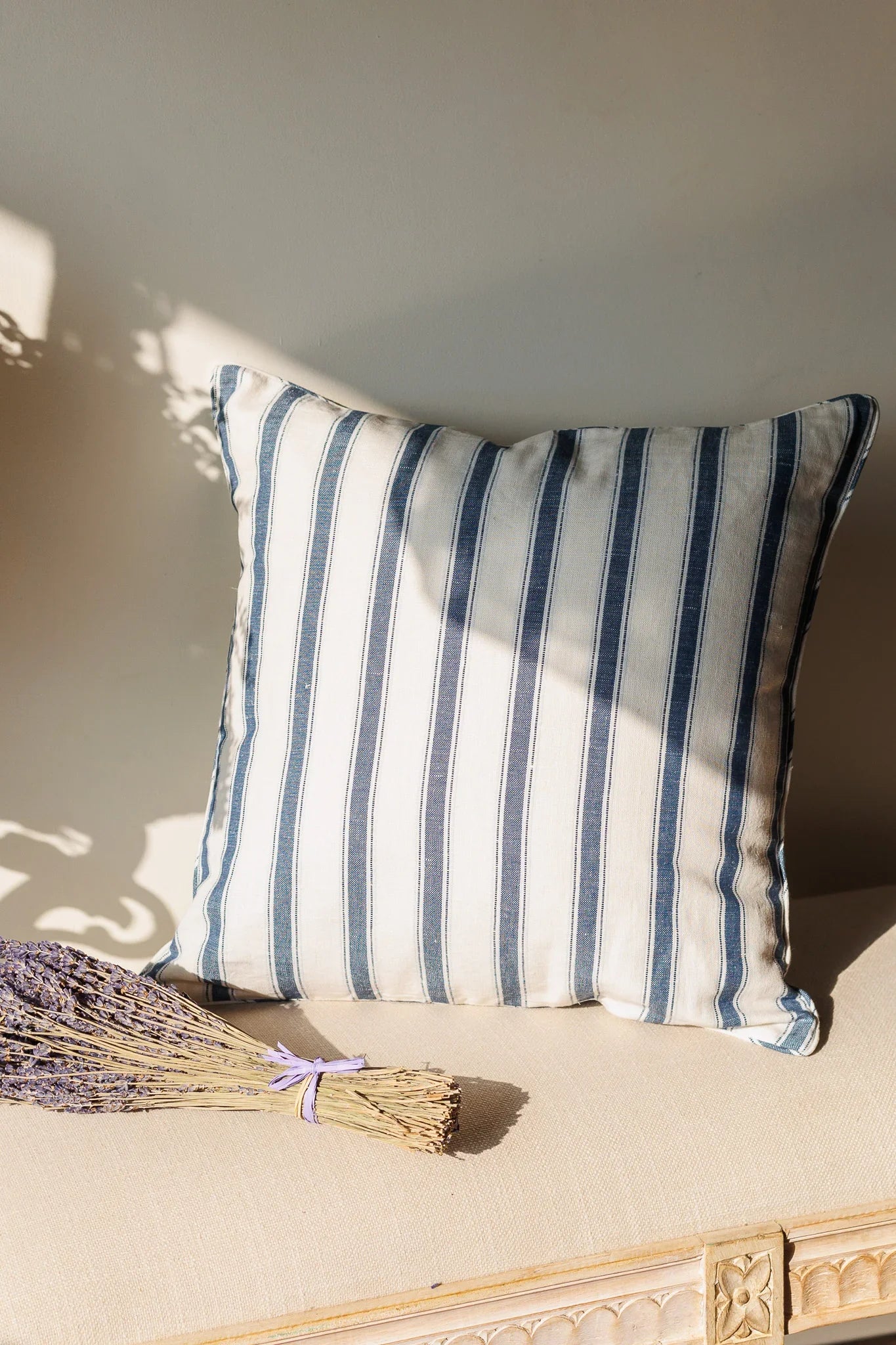 Striped cushion on a beige surface with a bundle of lavender
