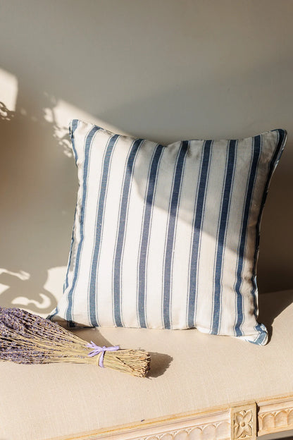 Striped cushion on a beige surface with a bundle of lavender