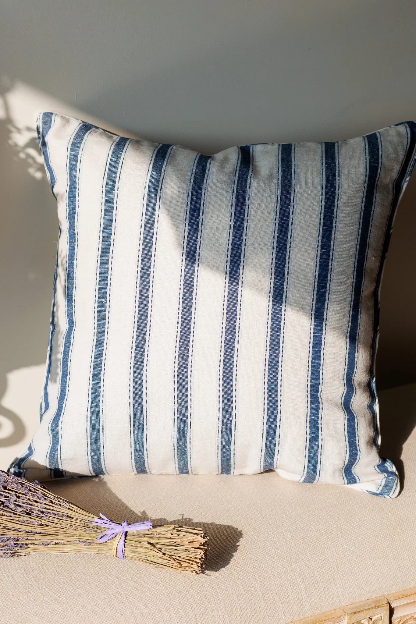 Striped cushion with blue and white stripes on a neutral background