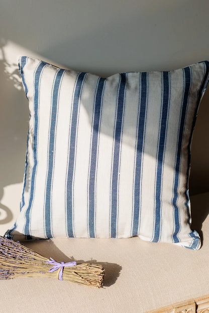 Striped cushion with blue and white stripes on a neutral background