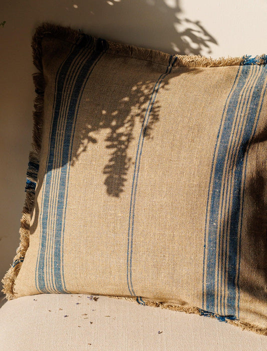 Blue stripes Linen Cushion Cover resting against a wall with sun and shadow over it