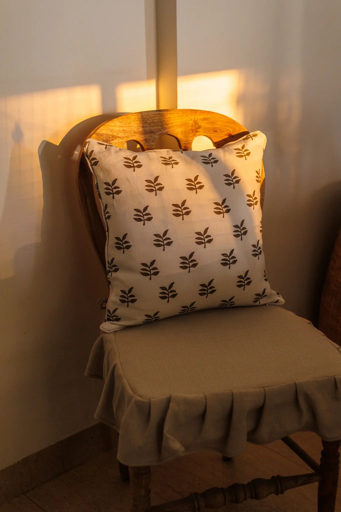 Chair with a patterned pillow under a lamp in a softly lit room