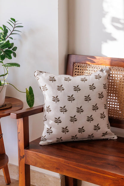 Decorative pillow with leaf pattern on a wooden bench next to a plant