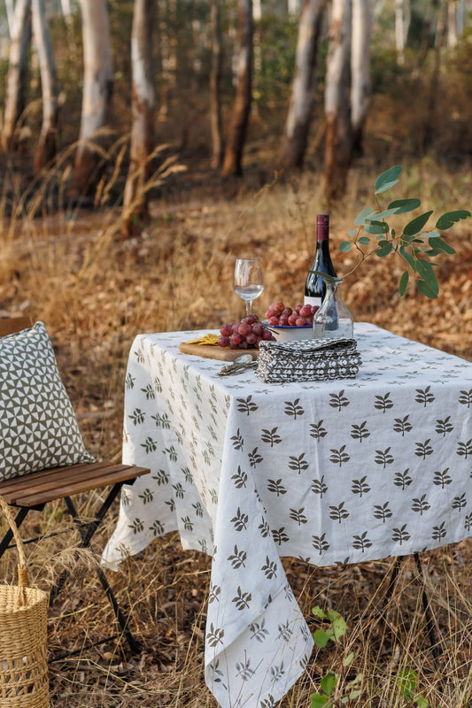 Picnic setup with a tablecloth, wine, and fruit in a natural setting