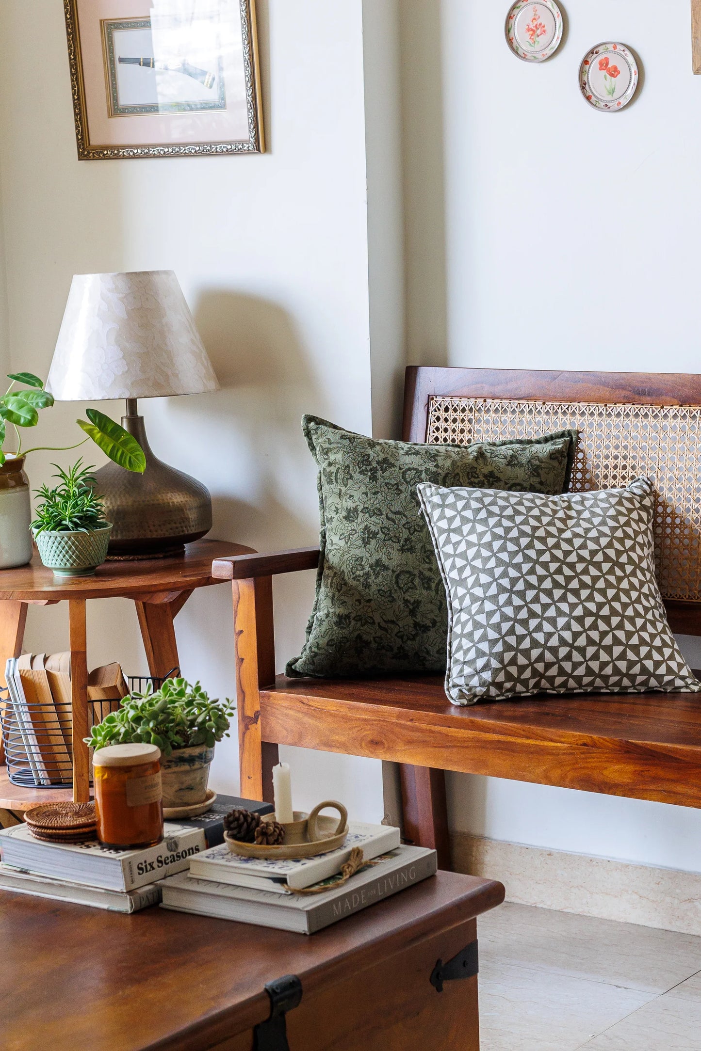 Living room corner with wooden bench, decorative pillows, and a lamp.