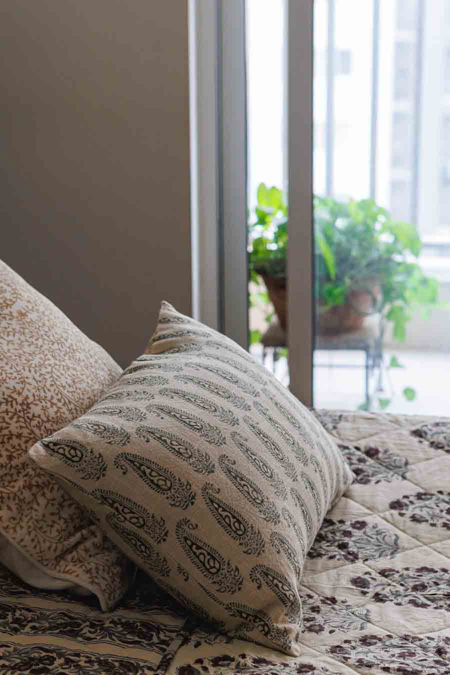 Paisley Block print  Cushion Cover with Block Print quilt placed on bed next to a window and plant