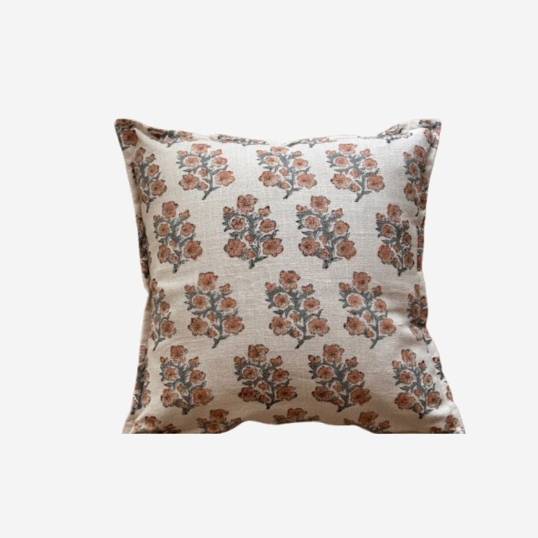 A square decorative cushion with a beige linen-like base and an all-over floral block print in muted terracotta orange and dark gray-green, shown against a plain light gray background.
