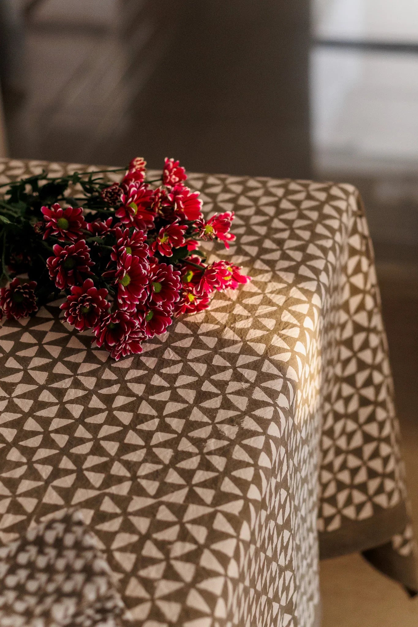 Bouquet of red flowers on a patterned tablecloth with a blurred background