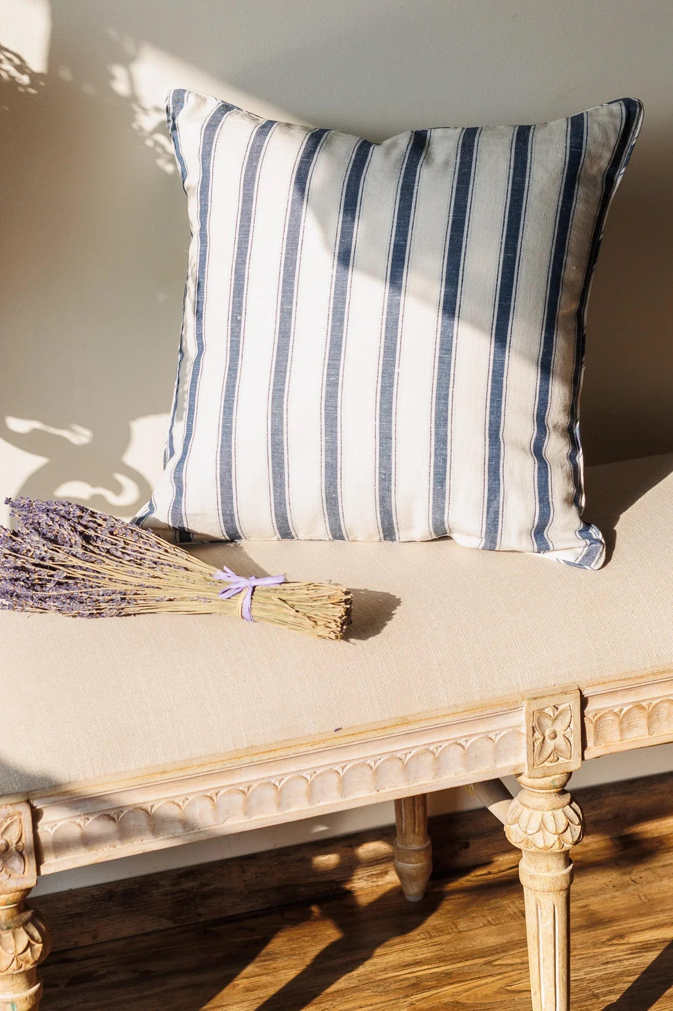 Striped Blue and white decorative cushion on a decorative bench with a bundle of lavender