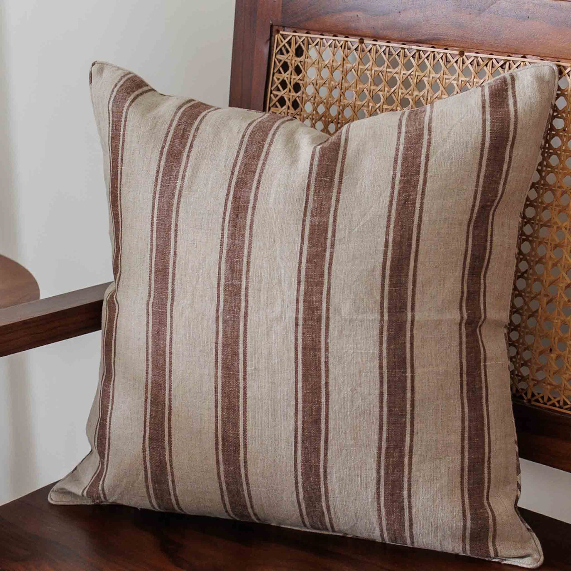 Square stripes Linen throw pillow on a rattan bench