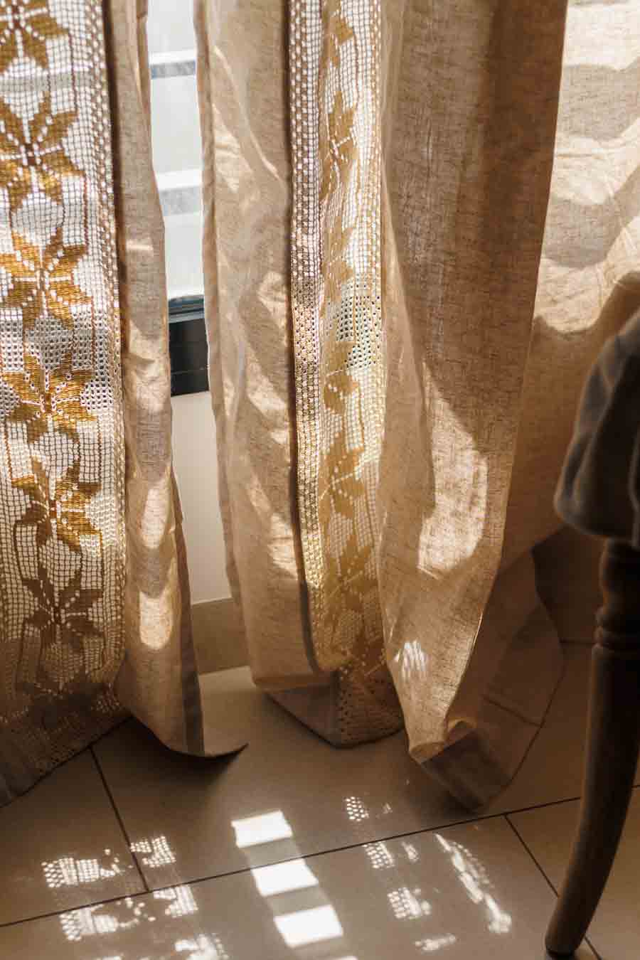 beige lace curtains close up with sunlight streaming through