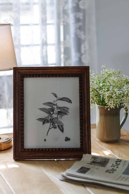 Wooden Frame on a table with a vase of flowers and newspaper