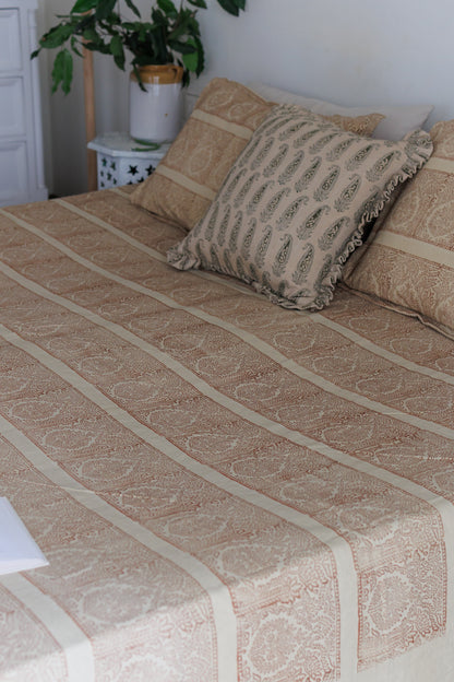 A bed with a beige and brown block printed cotton bed sheet with pillowcase.