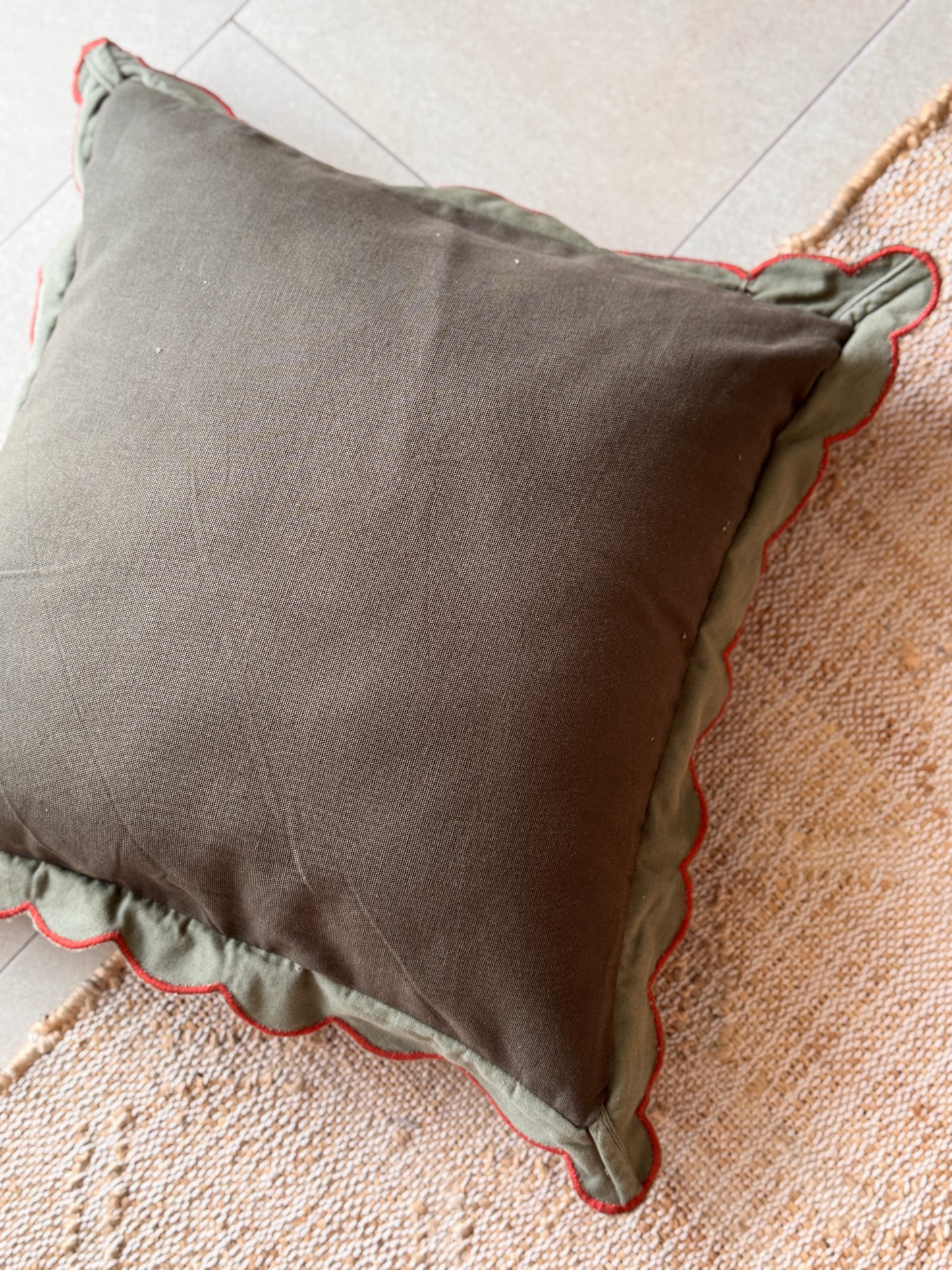 Gray pillow with red trim on a textured surface