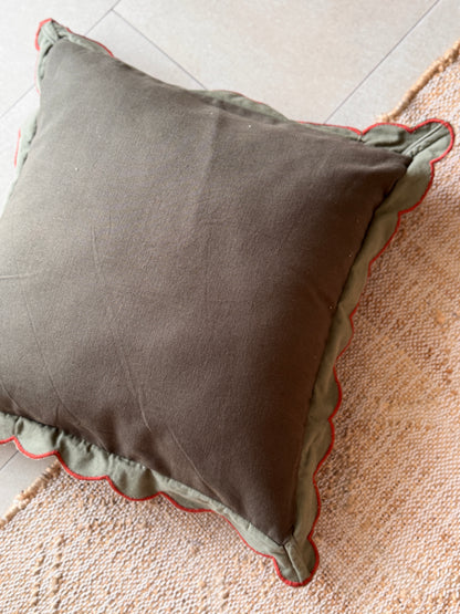 Gray pillow with red trim on a textured surface