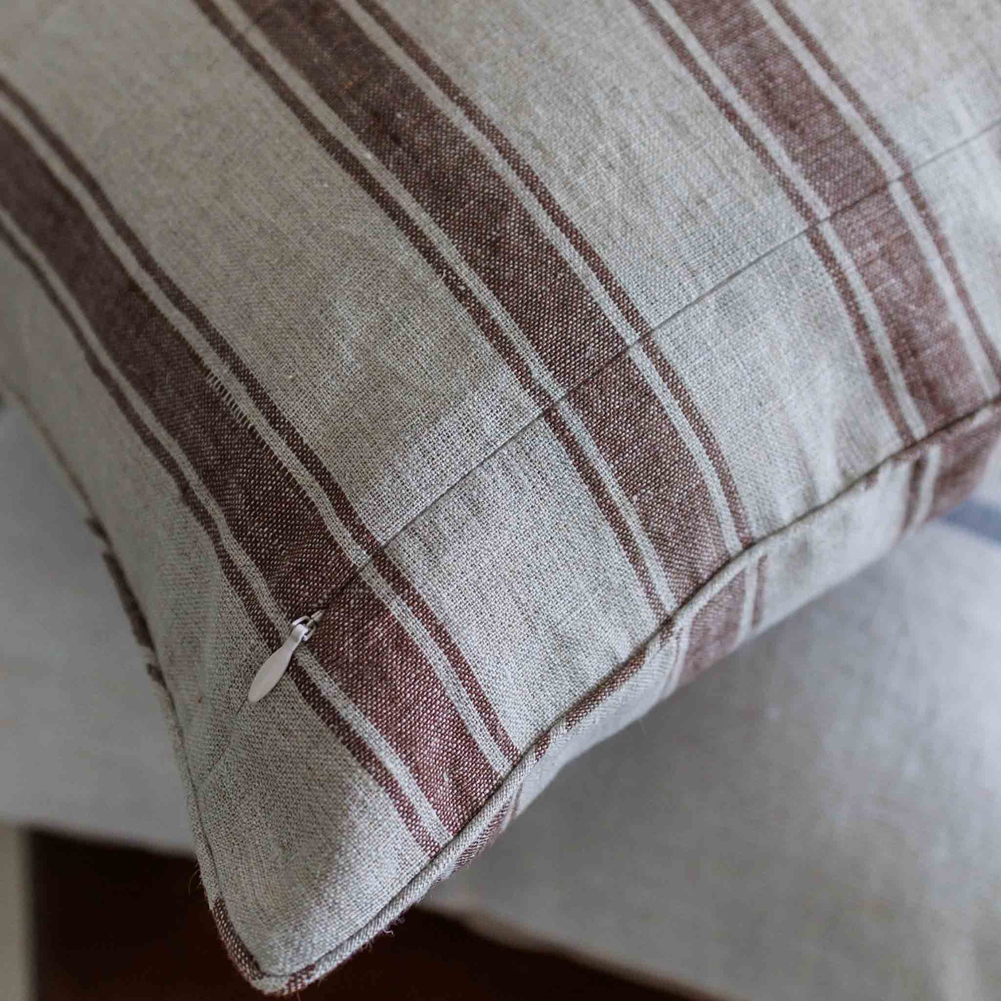A close-up of a linen cushion with a rustic striped pattern in brown and off-white linen fabric.