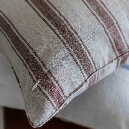 A close-up of a linen cushion with a rustic striped pattern in brown and off-white linen fabric.