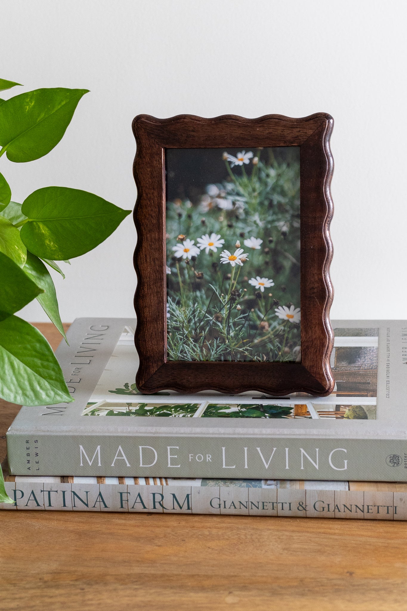 Wooden photo frame with a floral picture on top of books titled 'Made for Living'.