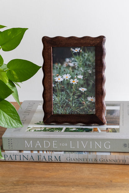 Wooden photo frame with a floral picture on top of books titled 'Made for Living'.